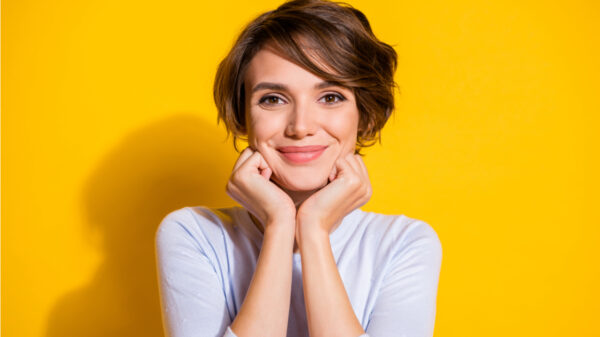 mulher de branco sorrindo em fundo amarelo