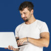Homem adulto em retrato de estúdio usando dispositivo portátil.