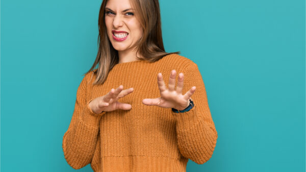Mulher vestindo roupas casuais, com expressão de nojo, descontente e com medo, fazendo cara de nojo, com reação de aversão e com as mãos levantadas.