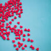 Em um fundo azul, um grande coração vermelho se divide em pedaços. Amor infeliz, sentimentos não correspondidos, decepção.