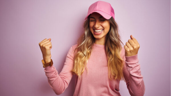 mulher feliz usando boné rosa em fundo rosa