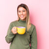 Jovem mulher segurando um café feliz, sorridente e alegre.