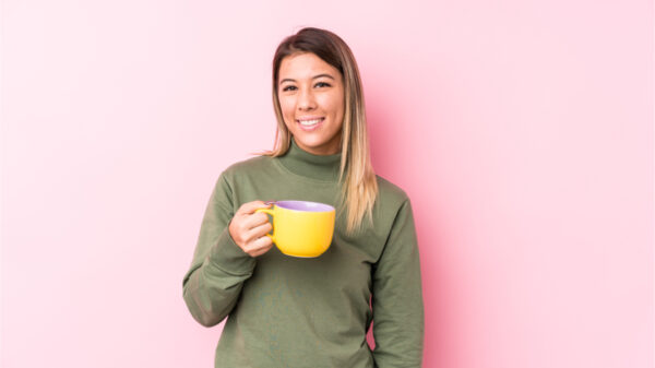 Jovem mulher segurando um café feliz, sorridente e alegre.
