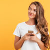 mulher segurando um celular em fundo amarelo