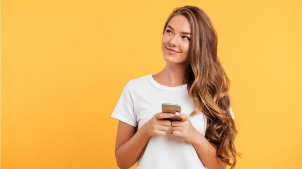 mulher segurando um celular em fundo amarelo
