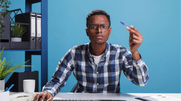Administrador de escritório suspeito, inseguro, com caneta na mão, parecendo desconfiado no monitor do computador. Conselheiro financeiro confuso, duvidoso, analisando estatísticas financeiras do projeto.