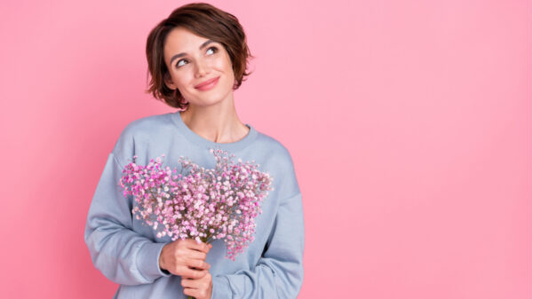 mulher segurando flores em fundo rosa