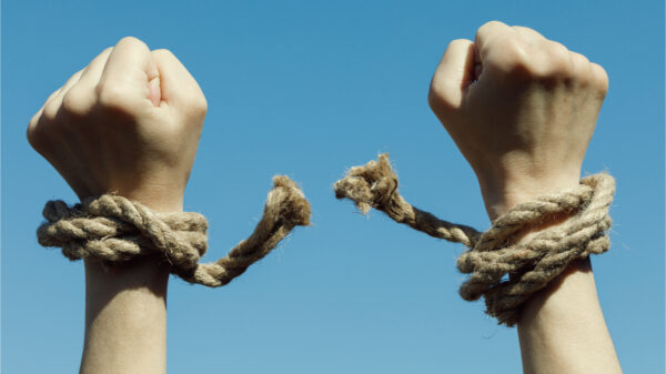 Mãos arrebentando corda no fundo do céu azul. Conceito de liberdade.