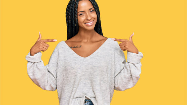 Mulher vestindo roupas casuais, parecendo confiante, com um sorriso no rosto, apontando-se com os dedos, orgulhosa e feliz.