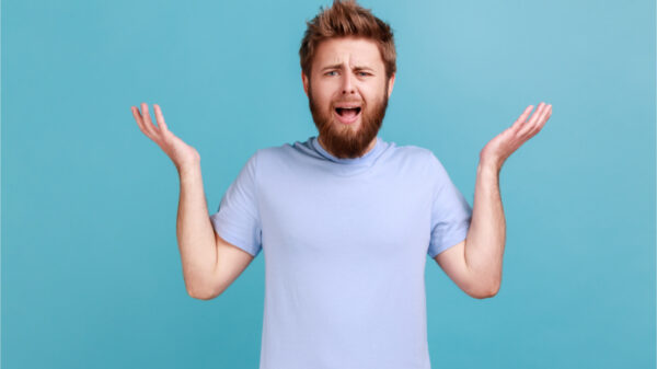 Retrato de homem barbudo frustrado e irritado, em pé, com as mãos levantadas e rosto indignado, perguntando por que, irritado com um problema. Foto de estúdio interior isolado sobre fundo azul.