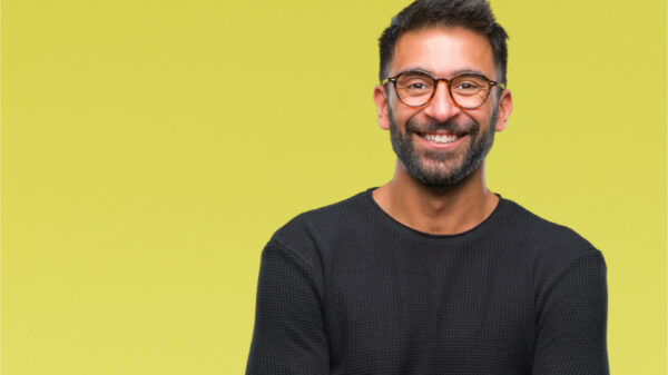Homem usando óculos sobre fundo isolado. Rosto feliz, sorrindo, com braços cruzados, olhando para a câmera. Pessoa positiva.