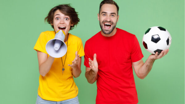 uma mulher feliz com megafone na mão e um homem com a bola na mão