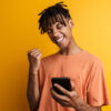 homem segurando um celular em fundo amarelo
