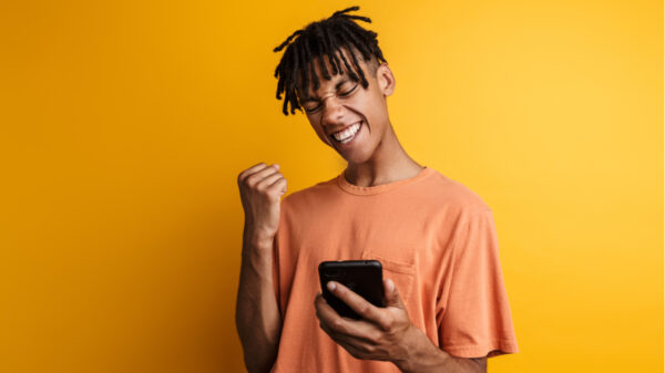 homem segurando um celular em fundo amarelo