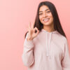 Mulher jovem vestindo uma roupa esportiva casual e fazendo um gesto de aprovação com a mão.