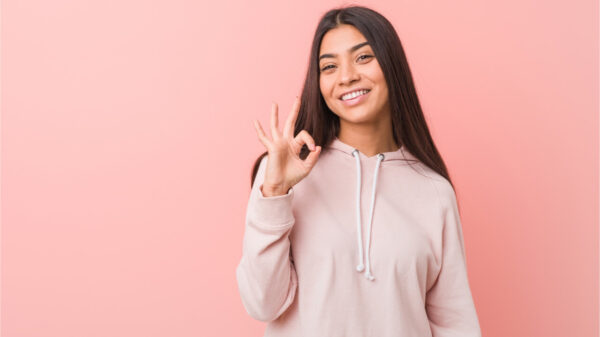 Mulher jovem vestindo uma roupa esportiva casual e fazendo um gesto de aprovação com a mão.