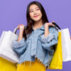 mulher segurando várias sacolas de compra em fundo roxo