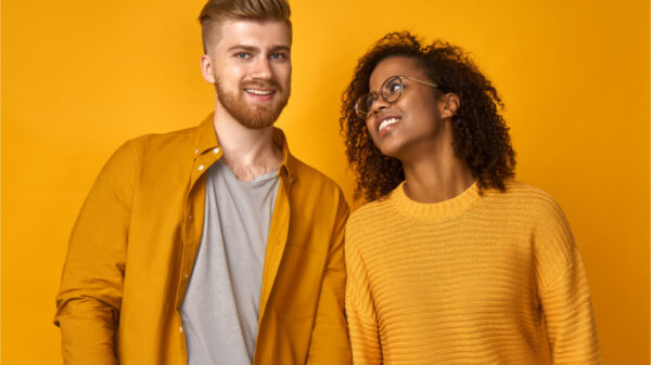 Expressões faciais e conceito de emoções positivas. Mulher feliz e sorridente e homem em roupas casuais, sorriem alegremente, satisfeitos em passar o tempo livre juntos, isolados na parede laranja.