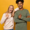 Foto de pessoas alegres, homem e mulher de cerca de 16 a 18 anos, isolados sobre fundo amarelo.