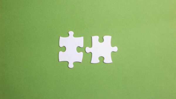 Duas peças de quebra-cabeça prestes a se conectar. Conceito de união e compatibilidade na equipe. Casal compatível. Símbolo de parceria e conexão. Fundo verde.