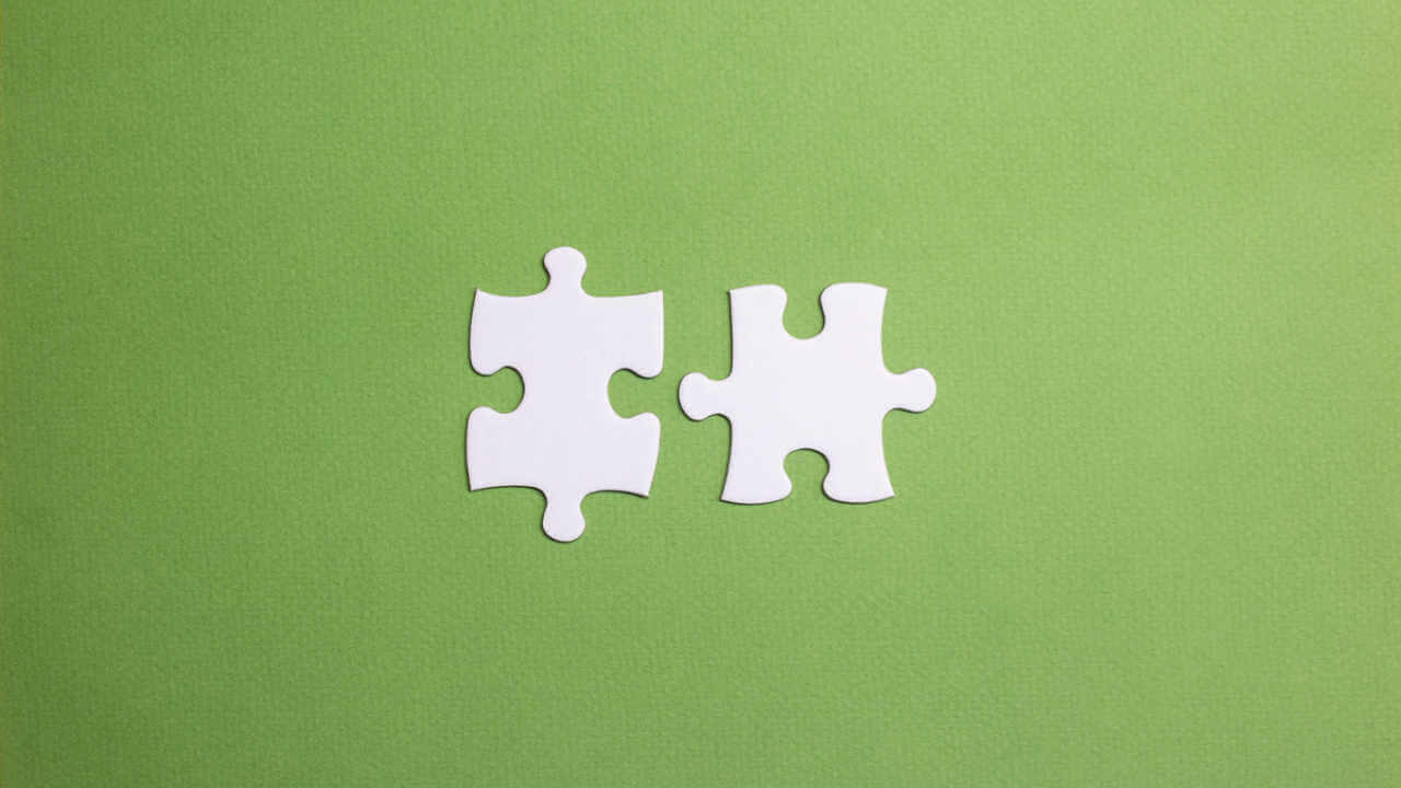 Duas peças de quebra-cabeça prestes a se conectar. Conceito de união e compatibilidade na equipe. Casal compatível. Símbolo de parceria e conexão. Fundo verde.
