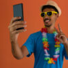 Homem fantasiado para o carnaval do Brasil, segurando celular, isolado em fundo laranja.