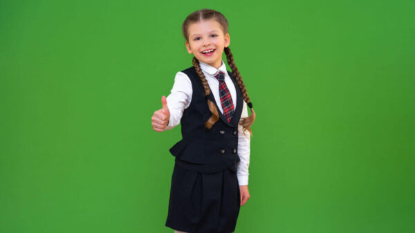 Menina alegre usando um uniforme escolar em um fundo isolado.