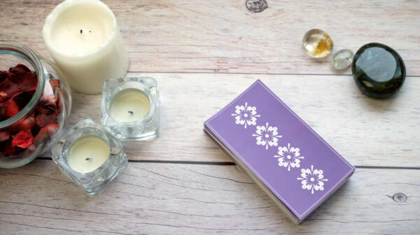 Baralho de cartas na mesa de madeira branca perto de velas e pedras preciosas. Conceito de leitura e previsão de cartomante.