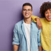 Homem e mulher sorrindo sobre fundo roxo.