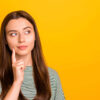 Foto de uma mulher com a intenção de entender algo, isolada em um fundo amarelo.