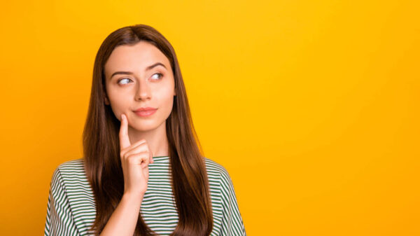 Foto de uma mulher com a intenção de entender algo, isolada em um fundo amarelo.