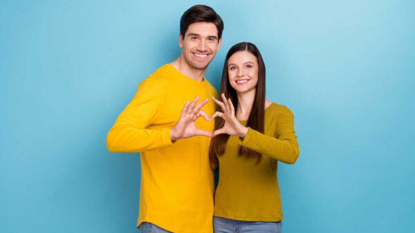 casal fazendo coração com as mãos em fundo azul