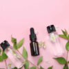 Potinhos de óleos essenciais, com flores de jasmim ao fundo. Cosmética natural e produtos para o cuidado do corpo e da mente. Vista superior, configuração plana.