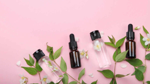 Potinhos de óleos essenciais, com flores de jasmim ao fundo. Cosmética natural e produtos para o cuidado do corpo e da mente. Vista superior, configuração plana.