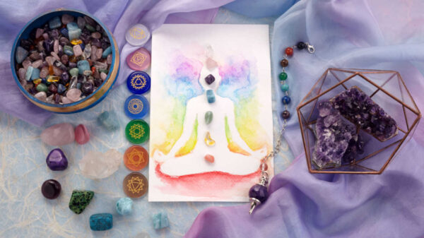 desenho do corpo humano em meditação e pedra e cristais nos pontos do chakras. Também há cristais em volta a figura