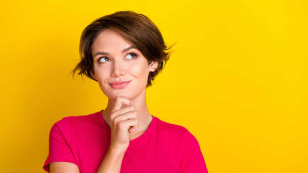 Foto de uma mulher usando uma blusa cor-de-rosa, isolada em um fundo de cor amarela.