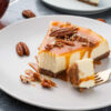 Pedaço de cheesecake clássico com calda de caramelo e nozes pecan.