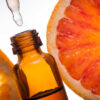 vidro de óleo essencial com uma laranja ao fundo