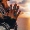 mulher com as mãos juntas e por do sol ao fundo