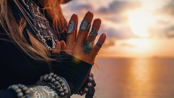 mulher com as mãos juntas e por do sol ao fundo