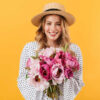 mulher loira segurando um buquê de rosas em um fundo amarelo