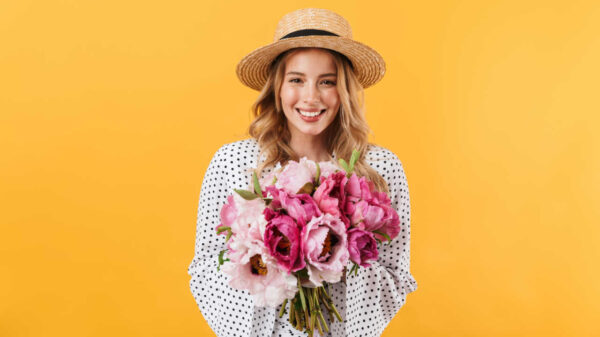 mulher loira segurando um buquê de rosas em um fundo amarelo