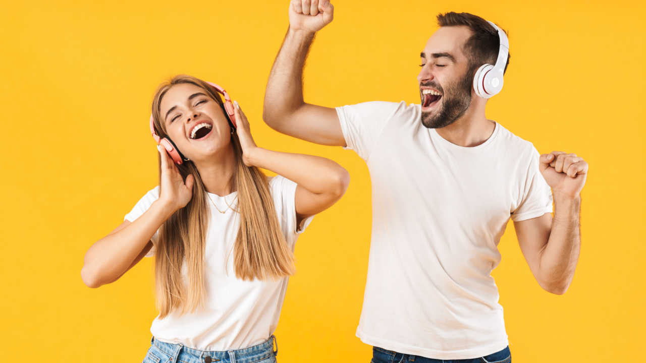 casal com fone de ouvido em fundo amarelo