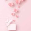 Corações saindo de uma caixa de presente. Elementos feitos de papel em um fundo rosa. Símbolos vetoriais de amor em forma de coração.