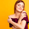 mulher se autoabraçando em fundo amarelo