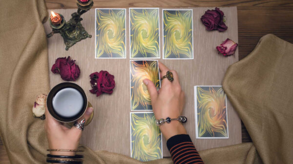 cartas de tarot em uma mesa com uma mão feminina em cima