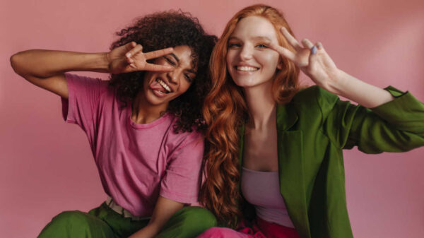 casal formado por uma mulher negra e uma mulher ruiva em fundo rosa