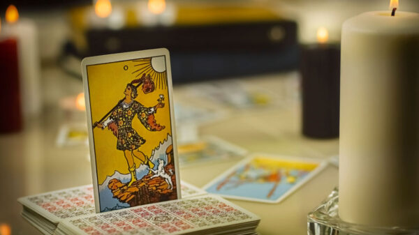 Cartas de tarô empilhadas e a carta dO Louco em pé, entre elas.