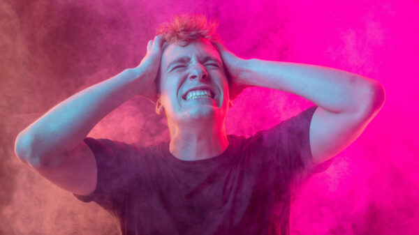 Dor emocional. Jovem emocionalmente instável, isolado sobre um fundo de cor magenta, com nuvens de fumaça. Conceito de saúde mental, de emoções humanas e de desafios.