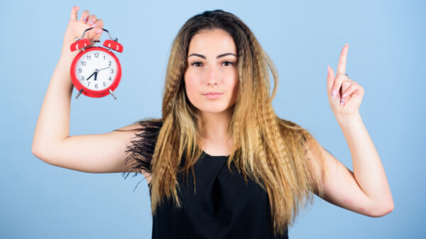 Conceito de gerenciamento de tempo; de pontualidade e disciplina. Mulher gerenciando seu tempo, segurando um despertador vintage.